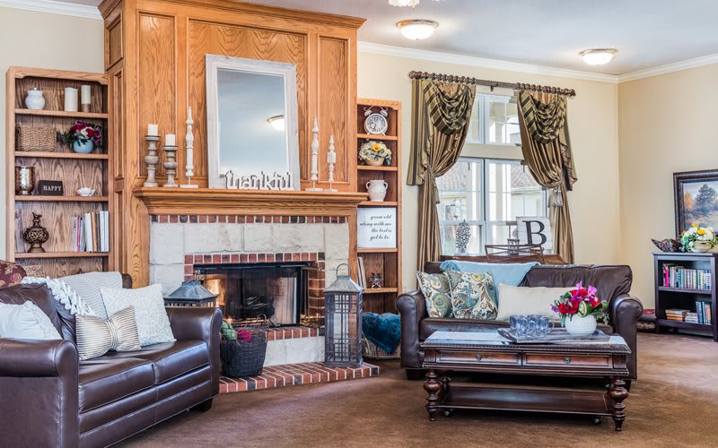 A cozy living room with a fireplace, leather sofas, and elegant decor.