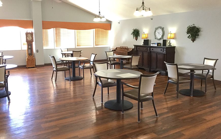 A modern dining area with hardwood floors and several tables and chairs set up for seating.