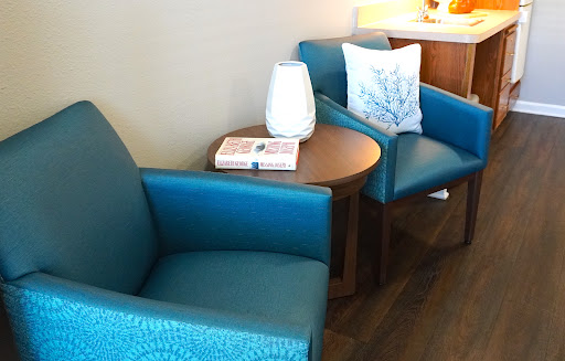 A cozy seating area featuring turquoise chairs and a wooden side table, perfect for relaxation.