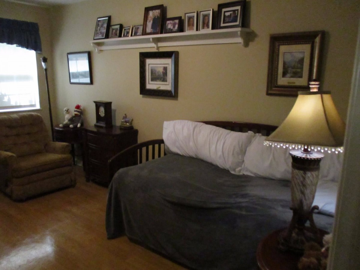 A cozy bedroom with a couch, adorned with picture frames and a lamp.
