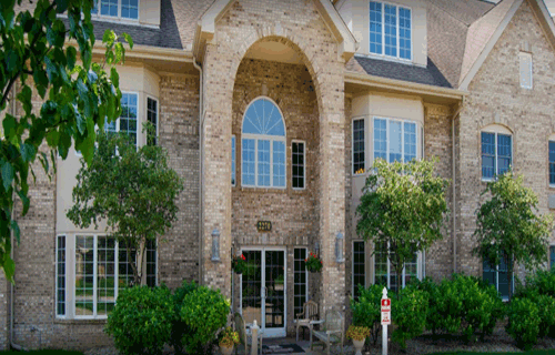 A stone-faced building with large windows and green landscaping.