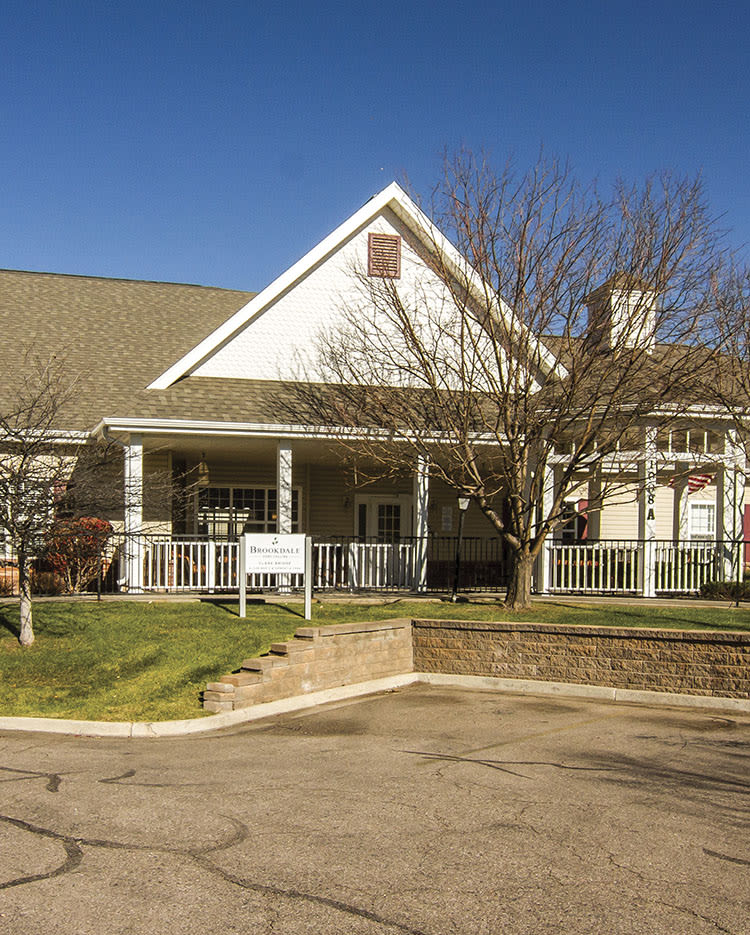 A large residential house with a spacious front porch and surrounding trees.