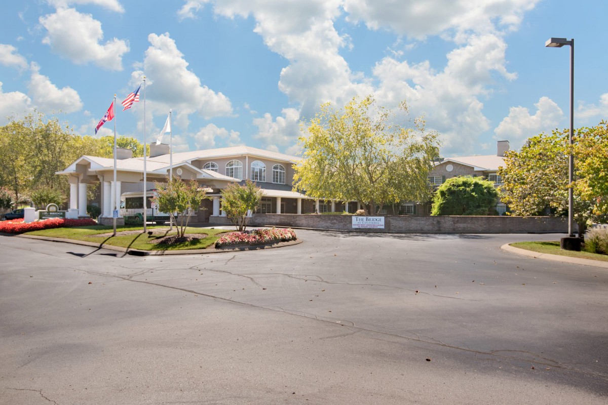 A building with flags outside, set against a backdrop of trees and a cloudy sky.