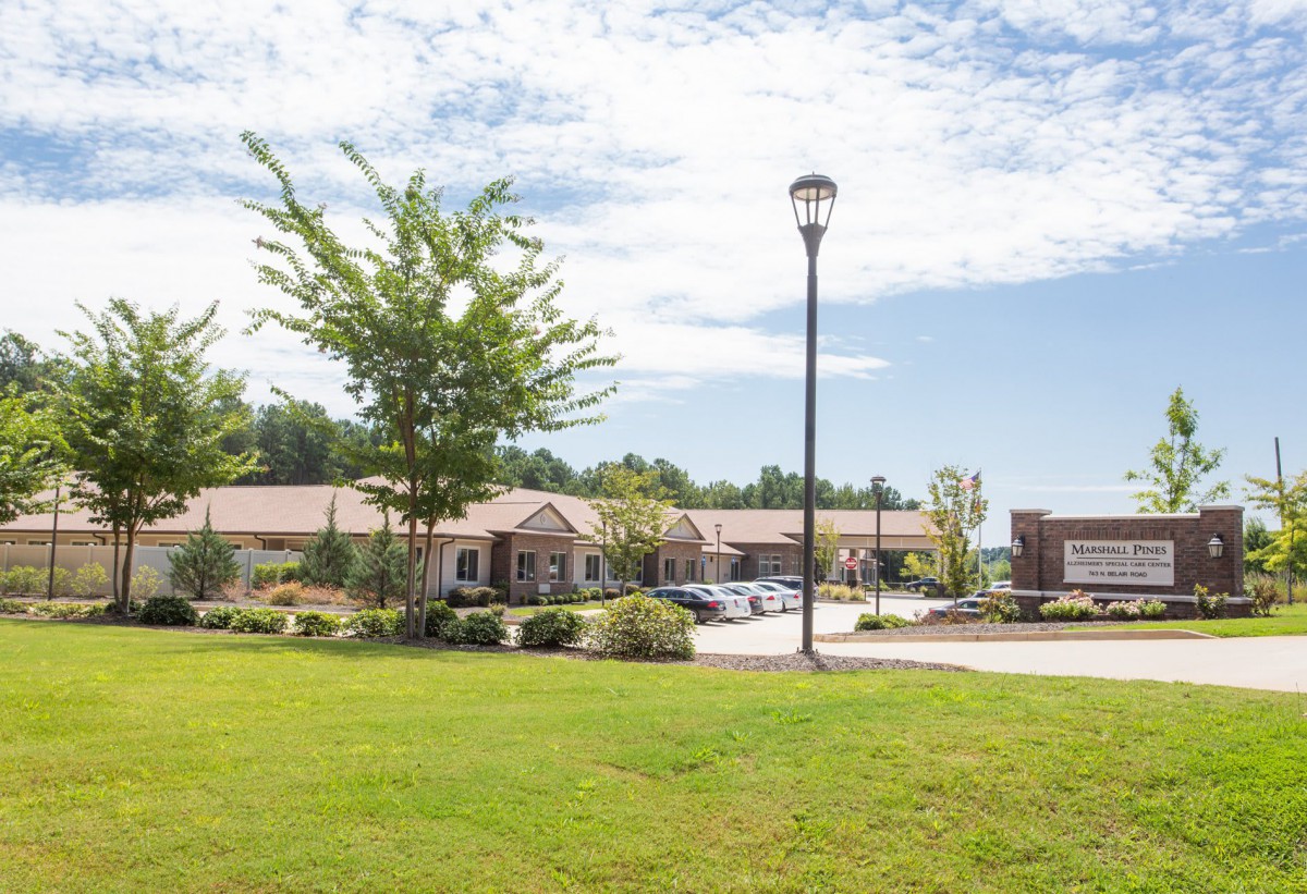 A scenic view of a building surrounded by trees and greenery under a partly cloudy sky.