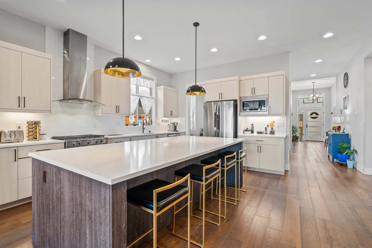 A modern kitchen with a large island, stylish pendant lights, and stainless steel appliances.