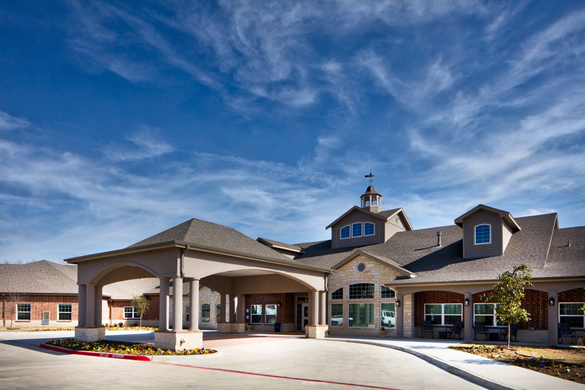 A large residential building with a covered entrance and a clear blue sky.