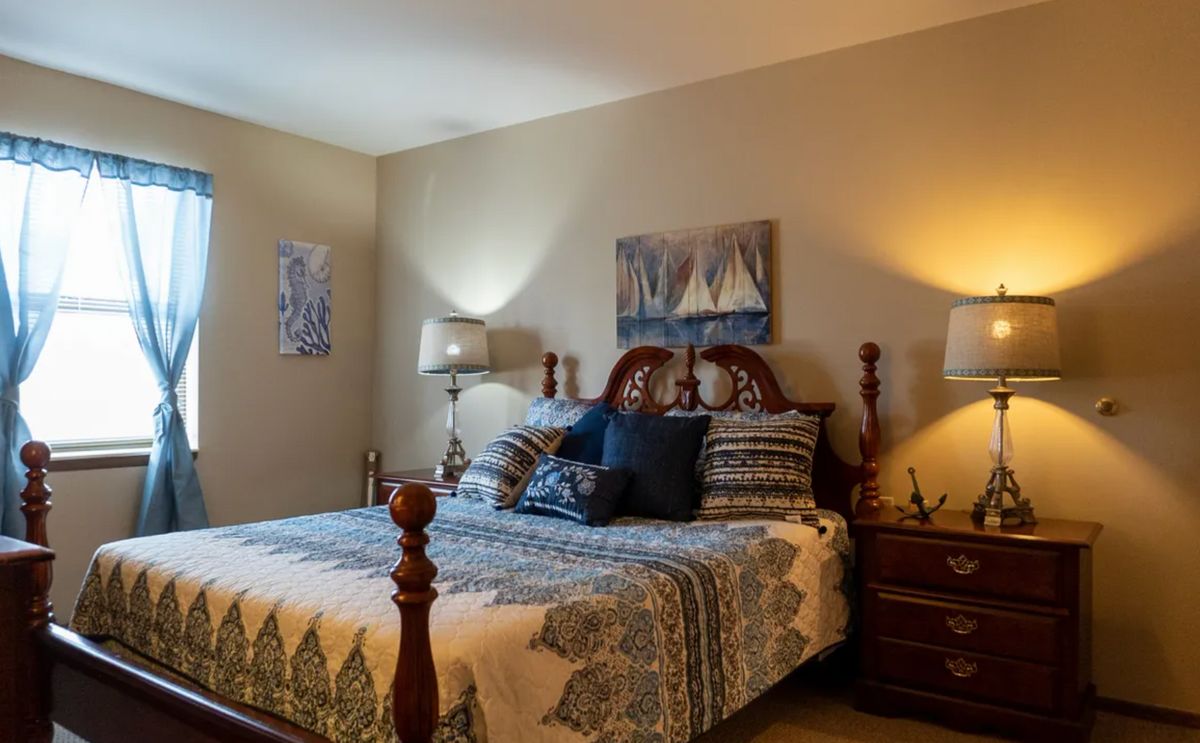 A cozy bedroom with a large bed, decorative pillows, and warm lighting.