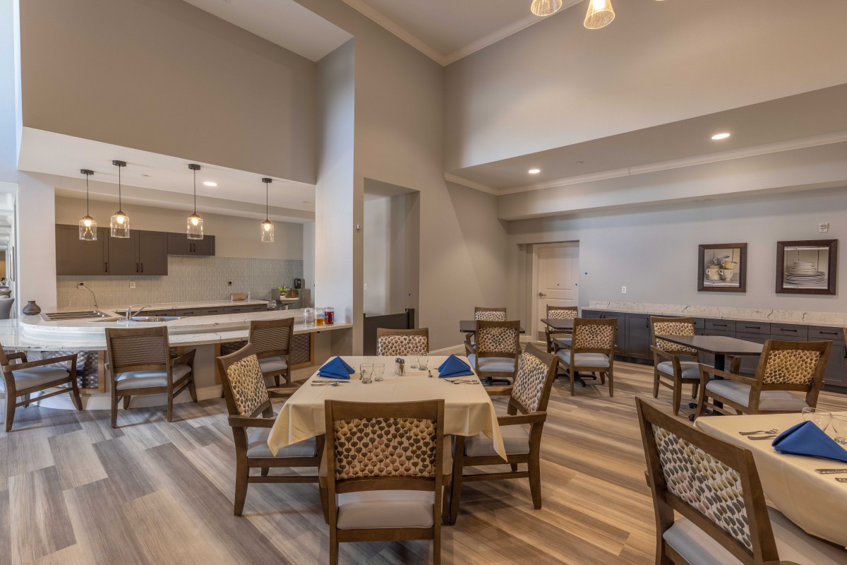 A modern dining area with neatly arranged tables and chairs, featuring ambient lighting.