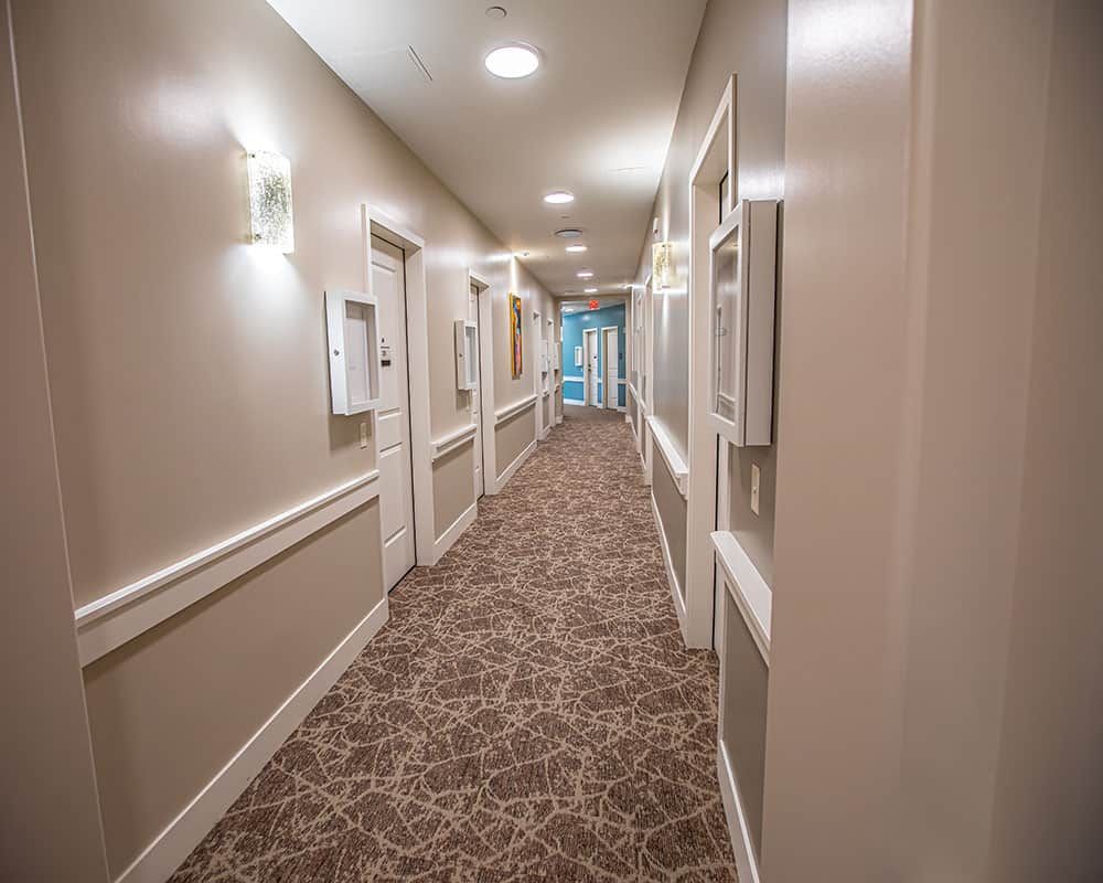A well-lit hallway with carpeted flooring and multiple doors.