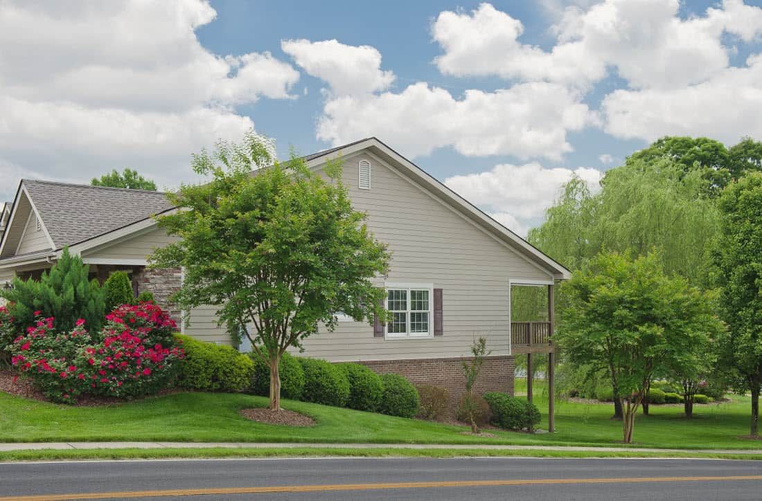 A suburban house with a well-maintained yard and trees, set against a cloudy sky.