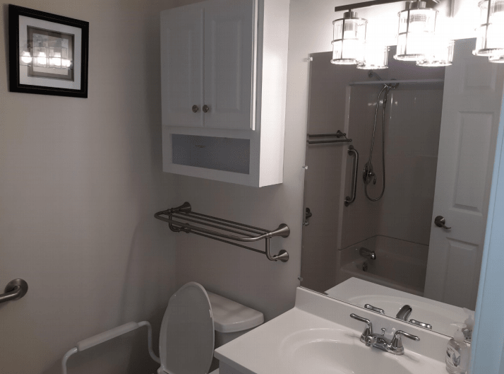 A modern bathroom featuring a sink, toilet, and shower with overhead lighting.