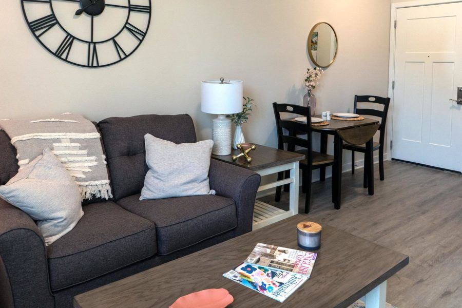 A cozy living room with a dark grey sofa, modern coffee table, and dining area.