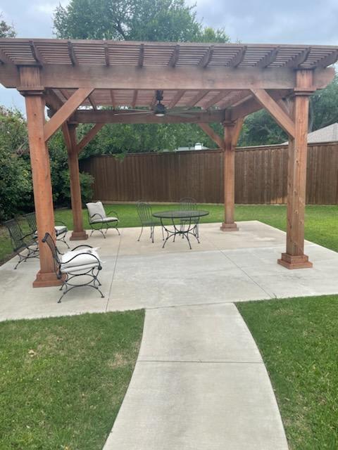 A backyard patio with a pergola and outdoor furniture.