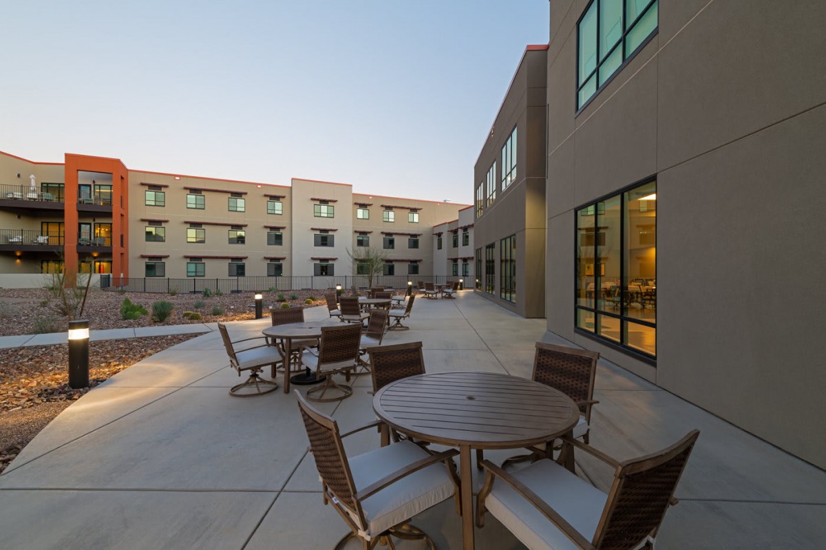 An outdoor patio area with tables and chairs adjacent to a modern building.