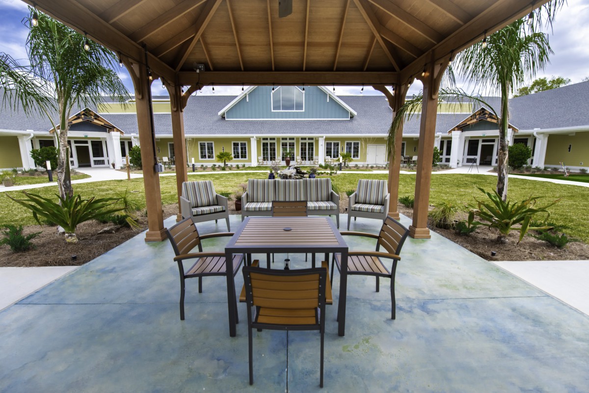 A cozy outdoor seating area under a gazebo with a view of a modern building in the background.