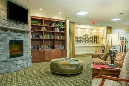 A cozy living room with a fireplace, bookshelf, and comfortable seating.