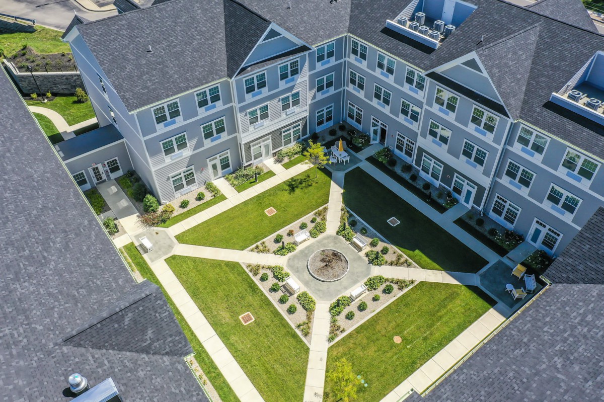 Aerial view of a well-maintained apartment complex with a central courtyard featuring pathways and greenery.