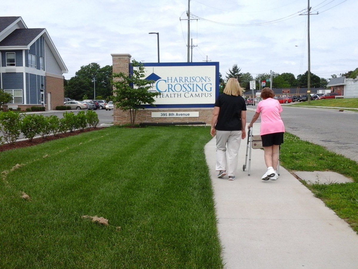 Two people walking towards a nursing home entrance.