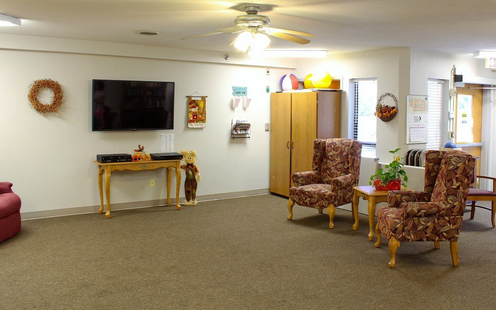 A cozy living room with a television, armchairs, and various decorations.