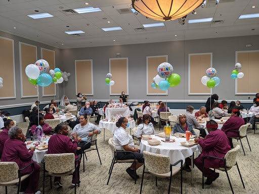 A lively gathering in a dining room decorated with balloons and filled with guests enjoying the celebration.