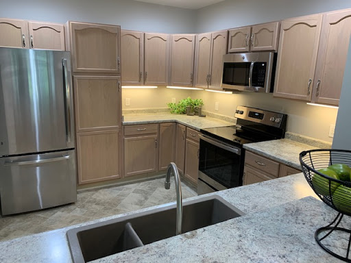 A modern kitchen featuring light wooden cabinets, stainless steel appliances, and a spacious countertop.