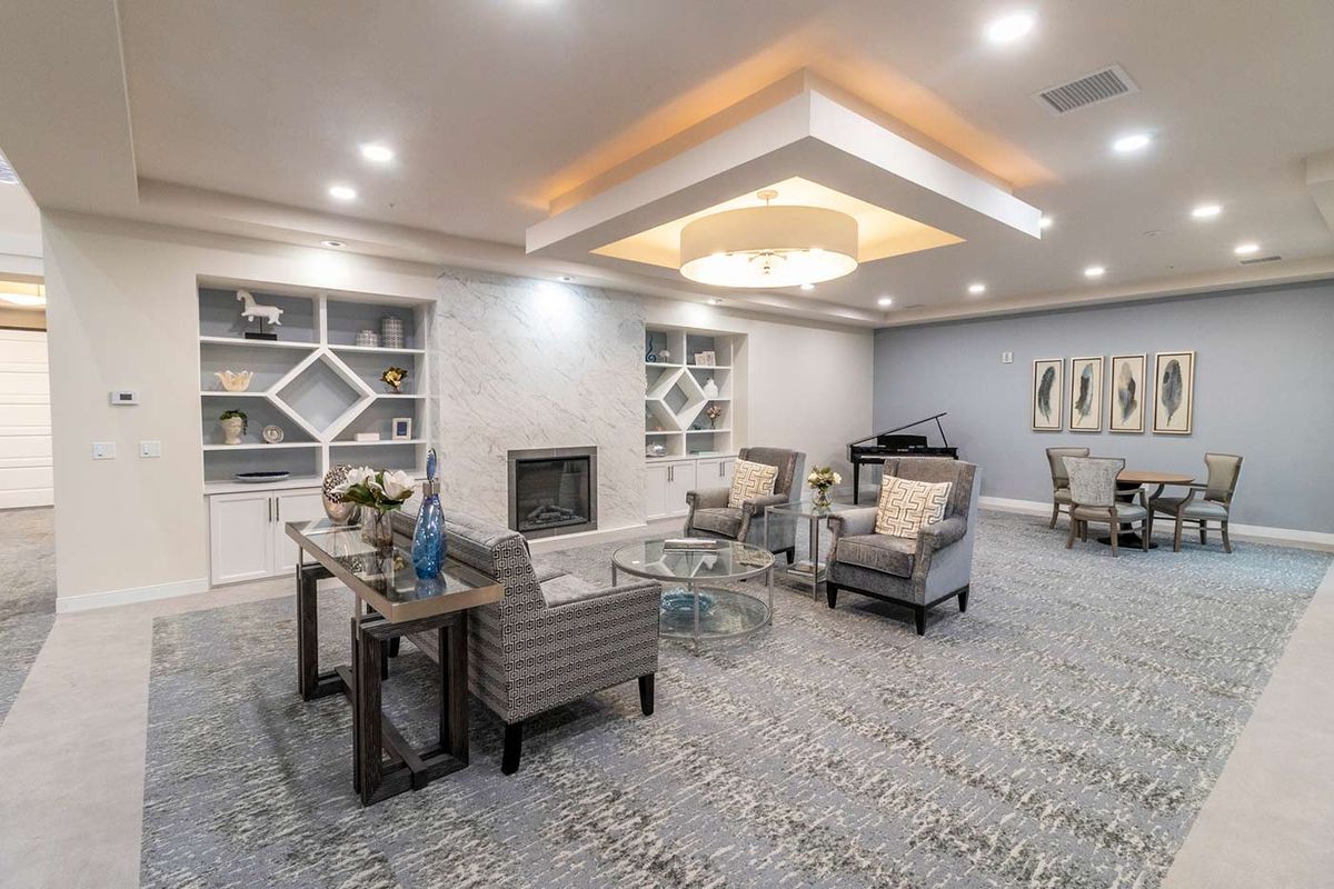 A modern living room with elegant furnishings, featuring a fireplace and a chandelier.