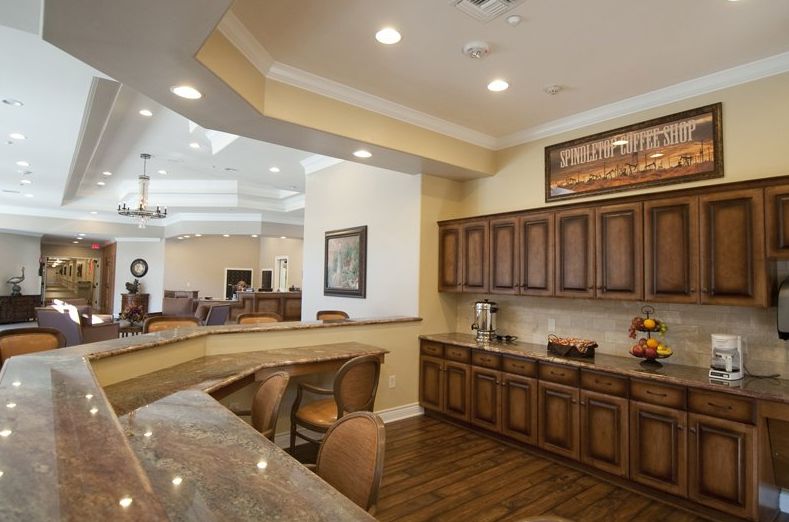 A spacious kitchen and dining area featuring wooden cabinets, a bar counter with chairs, and ambient lighting.