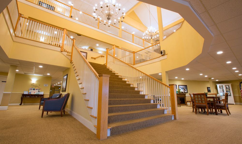 A spacious lobby featuring a grand staircase with wooden railings and a large chandelier.