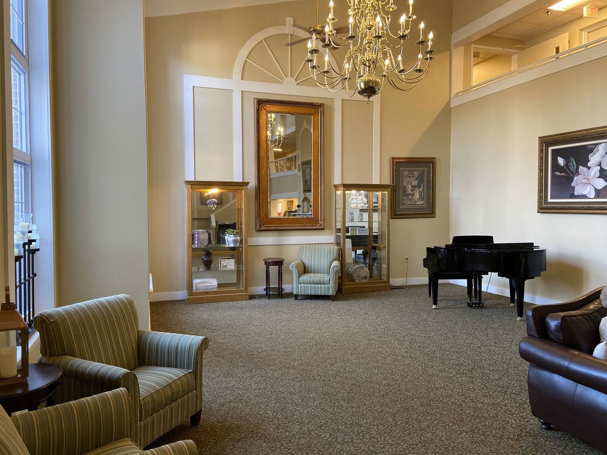 A spacious and elegantly decorated lounge area featuring a grand piano and chandelier.