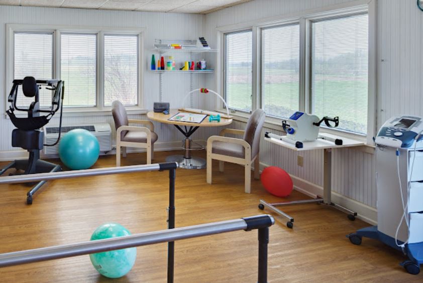 A physical therapy room equipped with exercise balls and parallel bars for rehabilitation exercises.