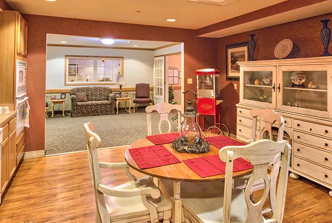 A cozy interior featuring a dining area with a wooden table and red placemats, adjacent to a living room with comfortable seating.