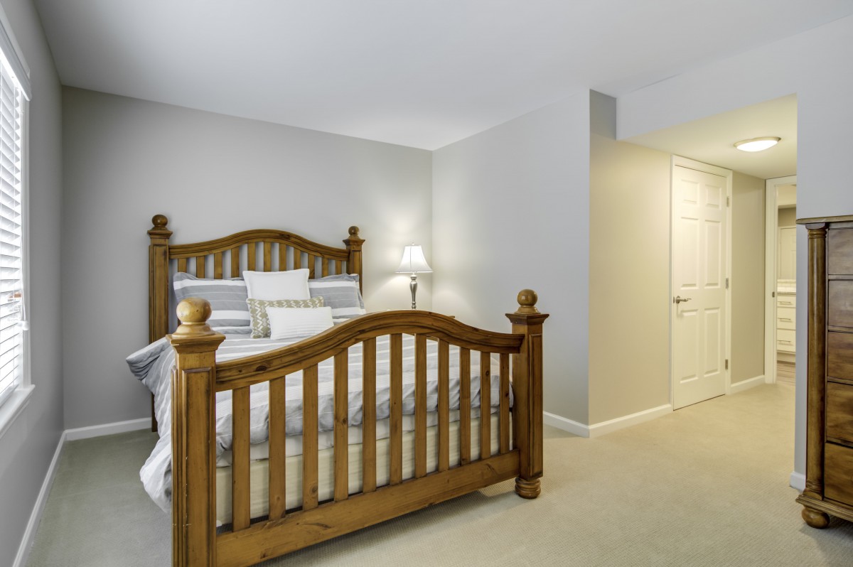 A cozy bedroom with a wooden bed frame and soft lighting.