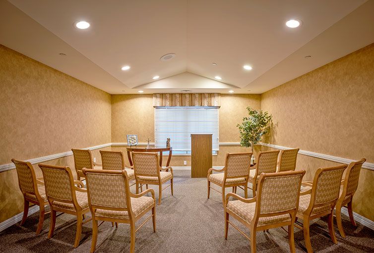 A small conference room with neatly arranged chairs facing a podium.