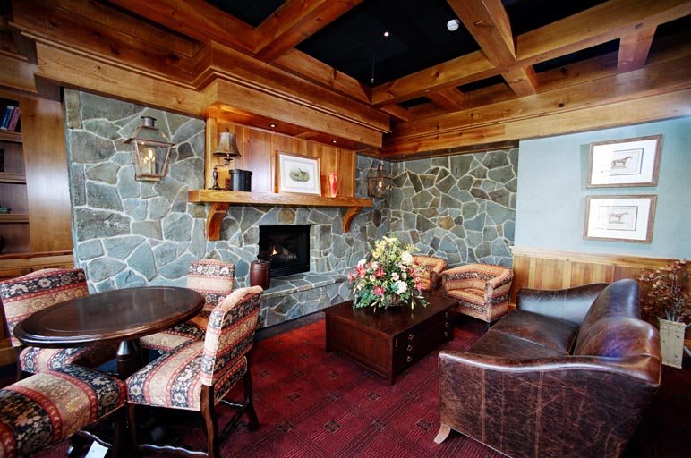 A cozy living room with a stone fireplace, wooden beams, and comfortable seating.