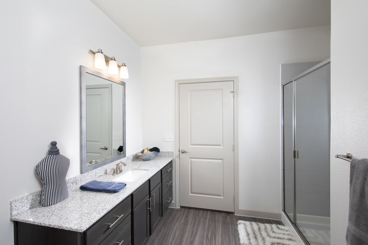 A modern bathroom featuring a large mirror, dual sinks, and a glass shower.
