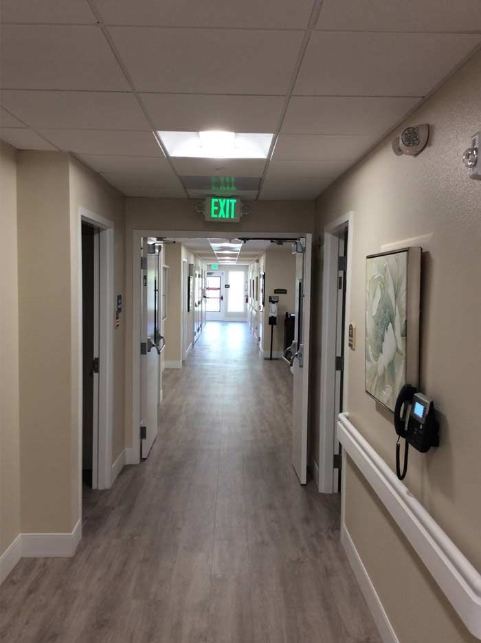 A well-lit hallway in a building with an exit sign and artwork on the walls.