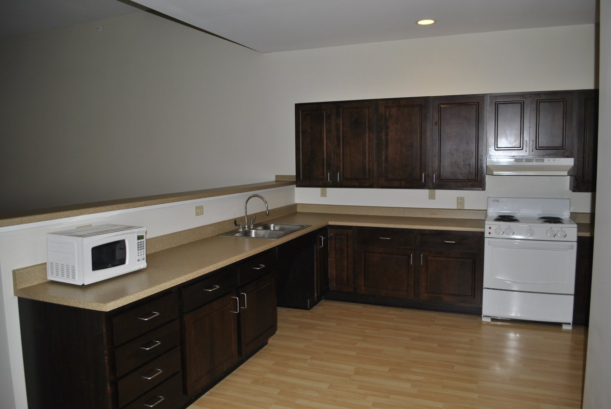 A modern kitchen with dark wood cabinets, a microwave, and an oven.