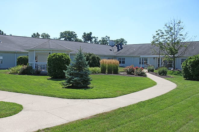 A single-story house surrounded by a well-maintained lawn and pathway.