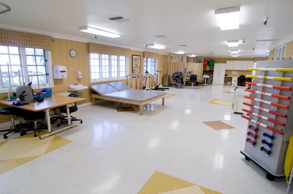 A spacious rehabilitation center equipped with therapy beds and exercise equipment.