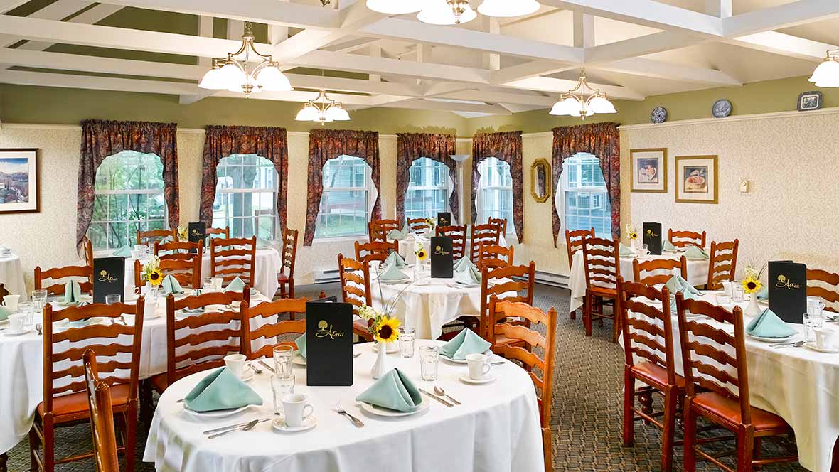An elegant restaurant dining area with neatly arranged tables and chairs, featuring white tablecloths and decorative place settings.