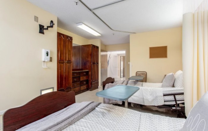 A hospital room featuring two neatly made beds with surrounding medical equipment and furniture.