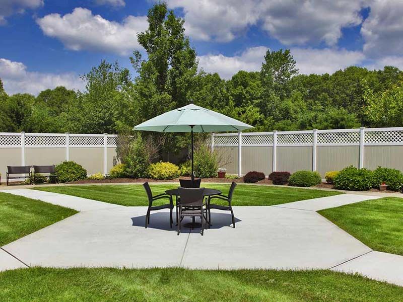 A serene backyard patio area with outdoor furniture, umbrella, and lush landscaping.