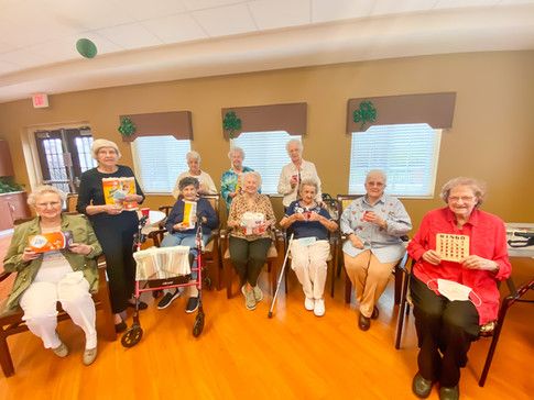 A group of seniors gathered together, smiling and socializing indoors.