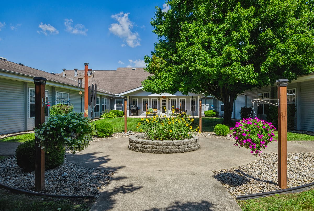 A tranquil courtyard garden with lush greenery and colorful flowers on a sunny day.