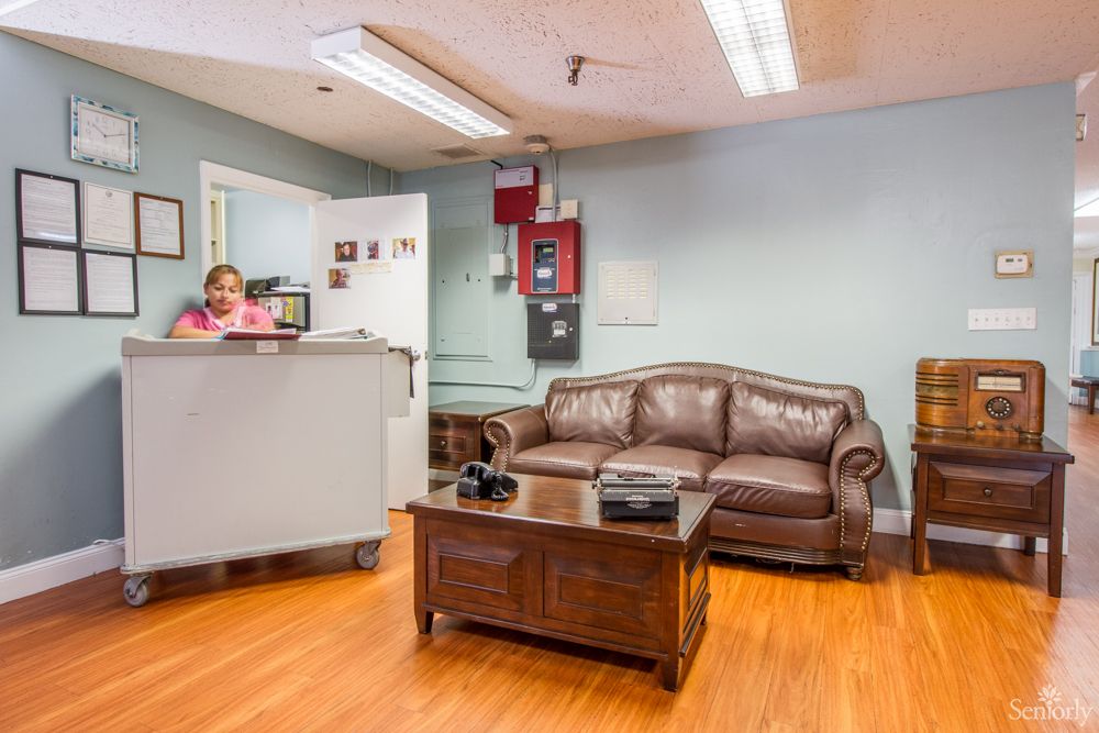 A cozy office waiting room with a sofa and receptionist desk.
