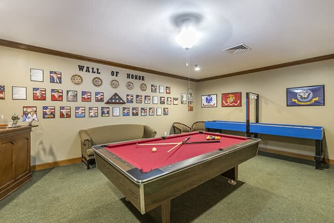 A cozy game room featuring a pool table, a 'Wall of Fame', and comfortable seating.