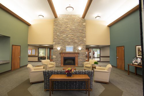 A modern and cozy lounge area featuring a central fireplace and comfortable seating.