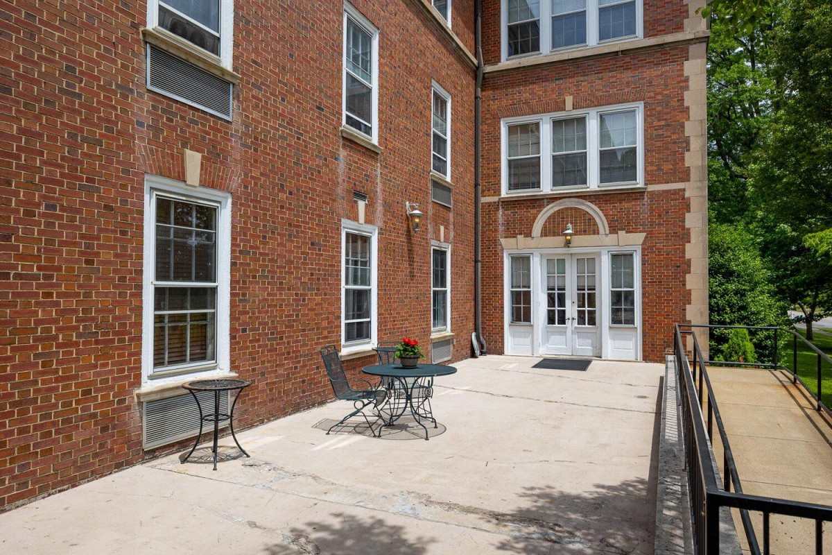 A sunny patio area with tables and chairs outside a brick building.
