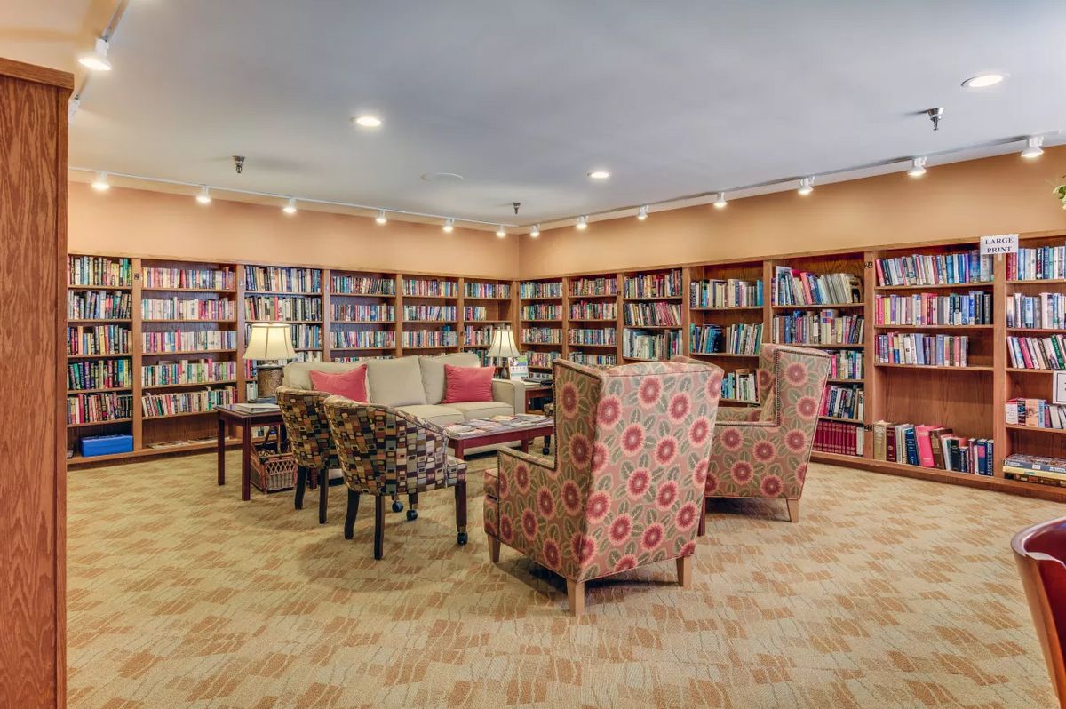 A cozy library reading room with comfortable chairs and bookshelves filled with books.