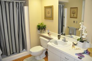 A well-lit bathroom featuring a toilet, sink, and shower with a blue curtain.